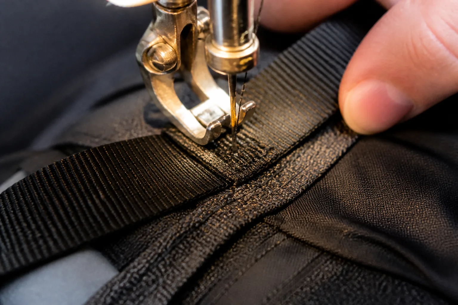 A repair stitch being sewn into a backpack seam with a reinforced bar tack and replaced webbing