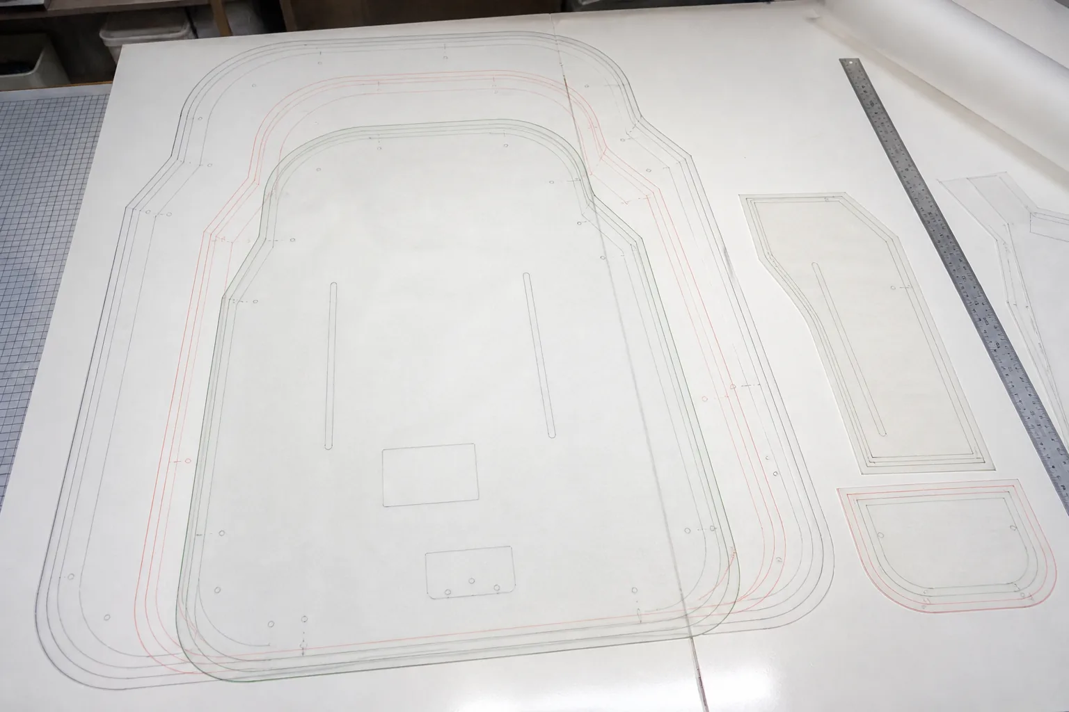 Nested graded pattern pieces for a backpack in three increasing sizes on a cutting table