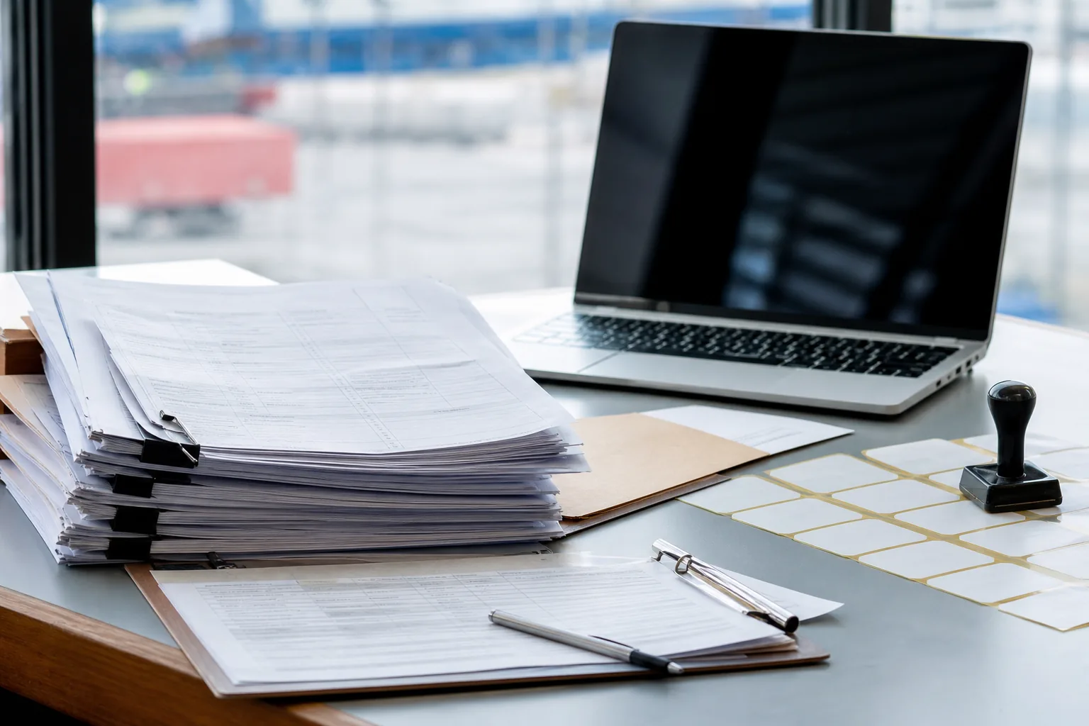 An export documentation desk with a stack of shipping documents, a folder and plain carton labels